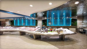 Banc marée inox et plafond suspendu en tôle embossée, avec mur de bulles éclairé, décor végétal au rayon poissonnerie trad.