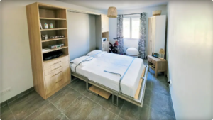 Agencement d’un lit escamotable double intégré à un meuble sur mesure avec plateau de bureau asservi au mécanisme d'ouverture