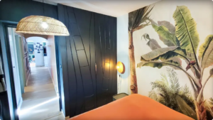 Placard sur mesure autour du tableau électrique, rainuré en rappel du décor mural végétal dans une chambre parentale.