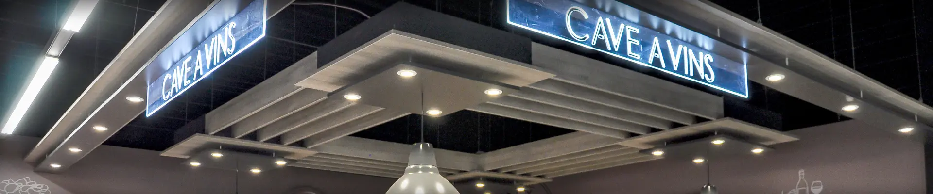 Un ciel de cave conçu et fabriqué par REYNIER Agenceur pour théâtraliser le rayon cave à vins d'un magasin alimentaire