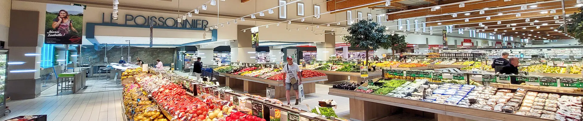 Du mobilier GMS dans le rayon frais d'un hypermarché : tables fruits et légumes, habillage sur mesure des arrières trad